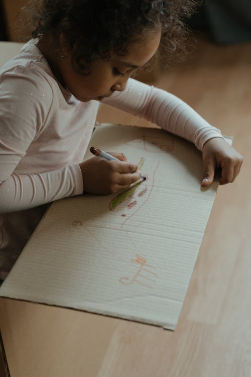 Girl in White Long Sleeve Shirt Writing on White Paper