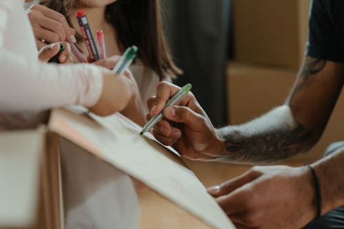 Free A family creatively decorates a moving box with colored markers during a move-in process. Stock Photo