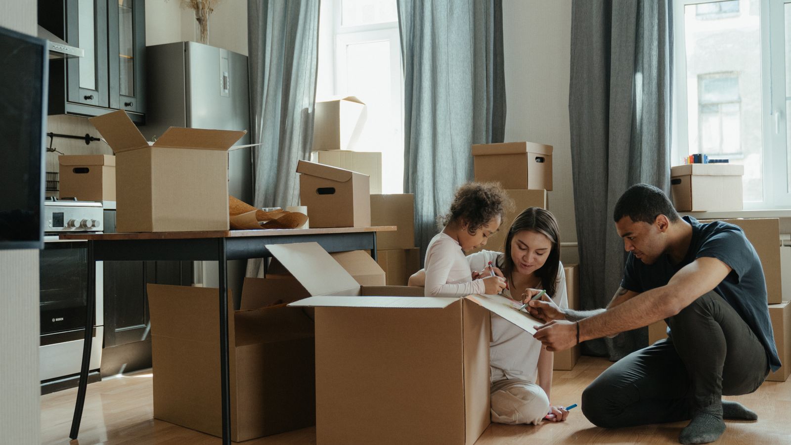Eine Familie packt gemeinsam Kartons in ihrem neuen Zuhause aus.