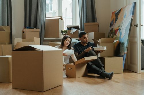 Free Couple unpacking cardboard boxes in a new apartment, surrounded by moving supplies. Stock Photo