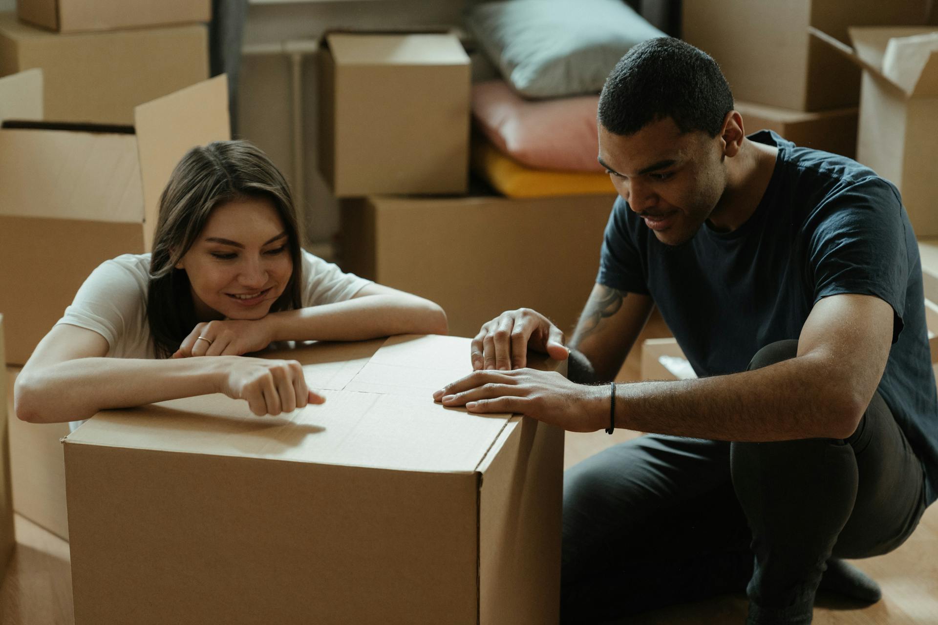 A joyful couple opening cardboard boxes in their new apartment, embracing a fresh start.