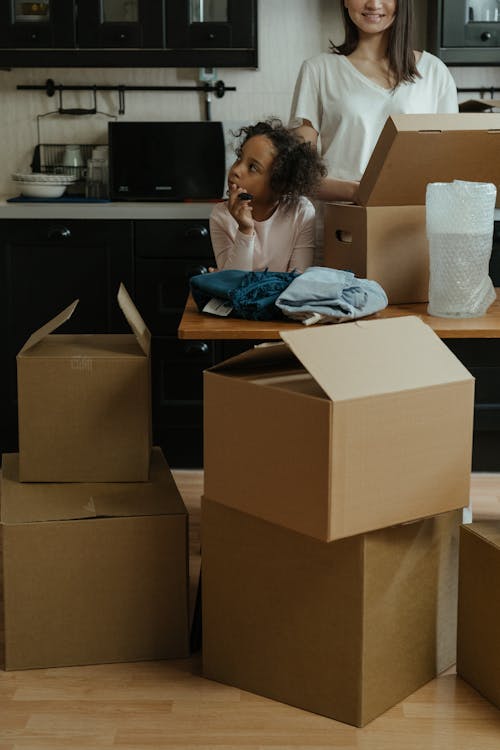 Woman in Blue Long Sleeve Shirt Sitting on Brown Cardboard Box