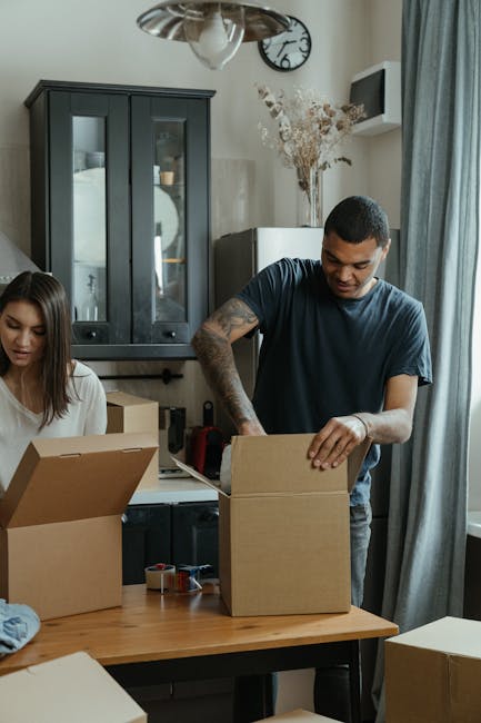 Man in Blue Crew Neck T-shirt Holding Brown Cardboard Box