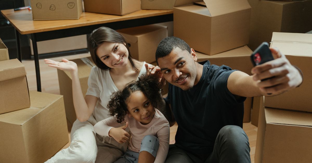 A joyful family taking a selfie amidst moving boxes in their new apartment.