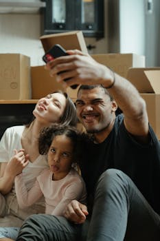 Joyful family taking a fun selfie on moving day surrounded by boxes.