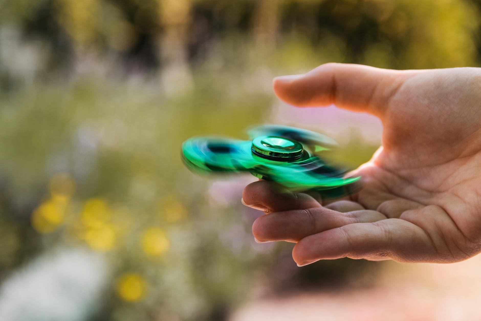Person Playing With Green Fidget Spinner