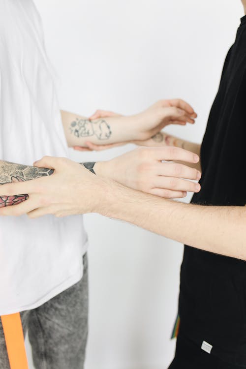 Free Person Holding Hands of a Person with Tattoo Stock Photo