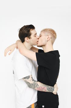 在白色背景下，一对年轻的同性恋夫妇温柔接吻，象征着爱与团结