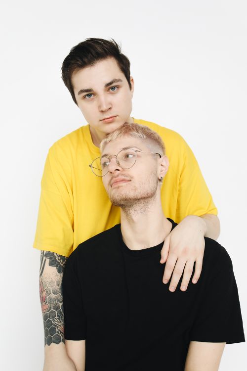 Free A modern LGBT couple sharing a tender embrace under soft indoor lighting. Stock Photo