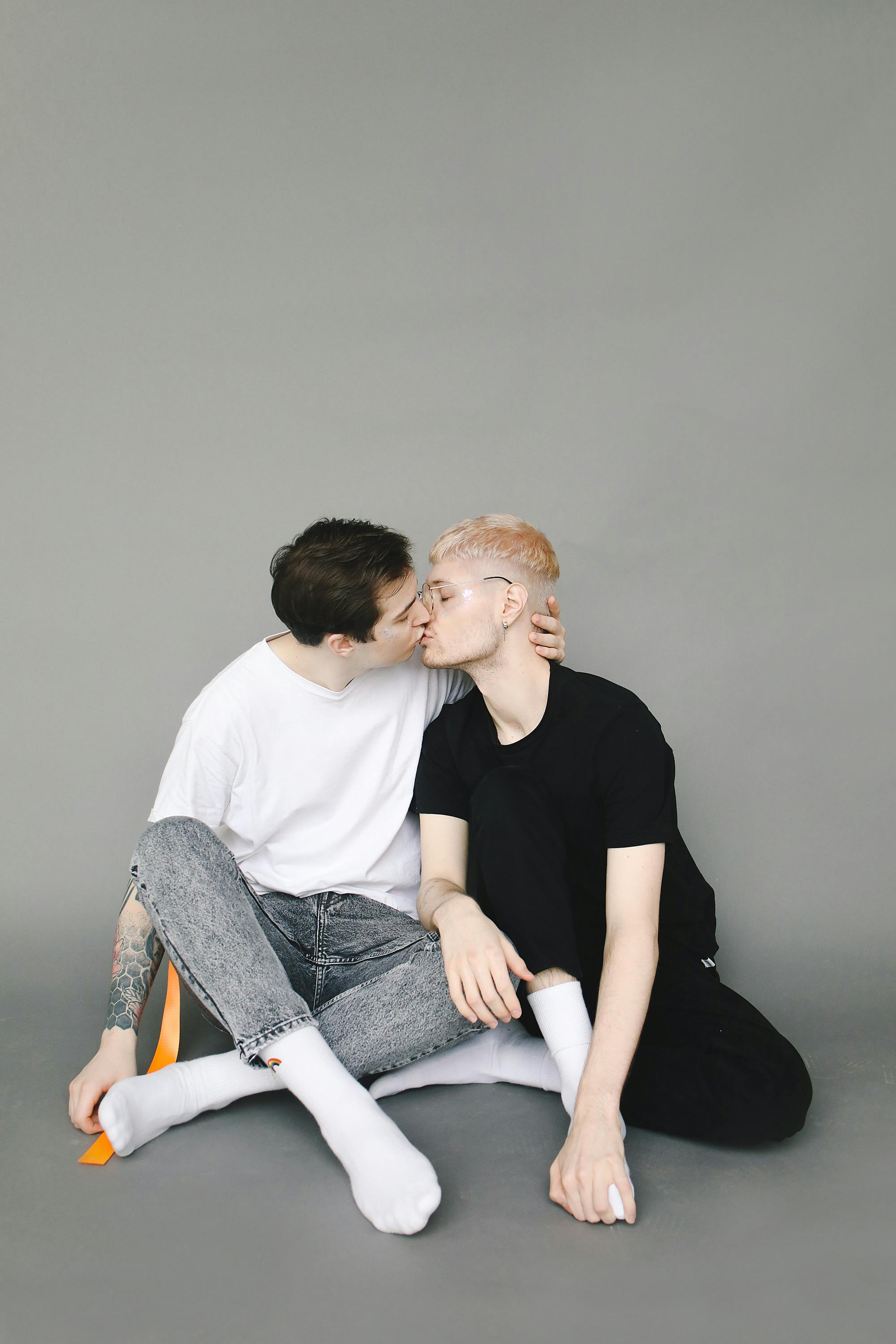 Мужчины сидят на полу и целуются · Бесплатные стоковые фото