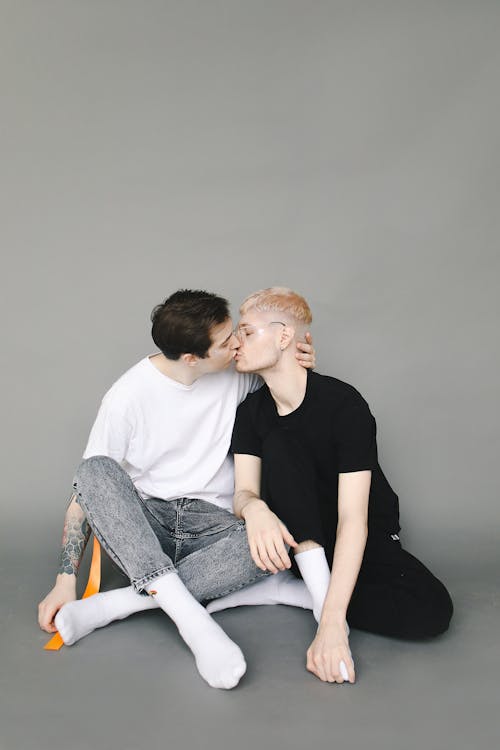 Free Men Sitting on the Floor and Kissing Stock Photo