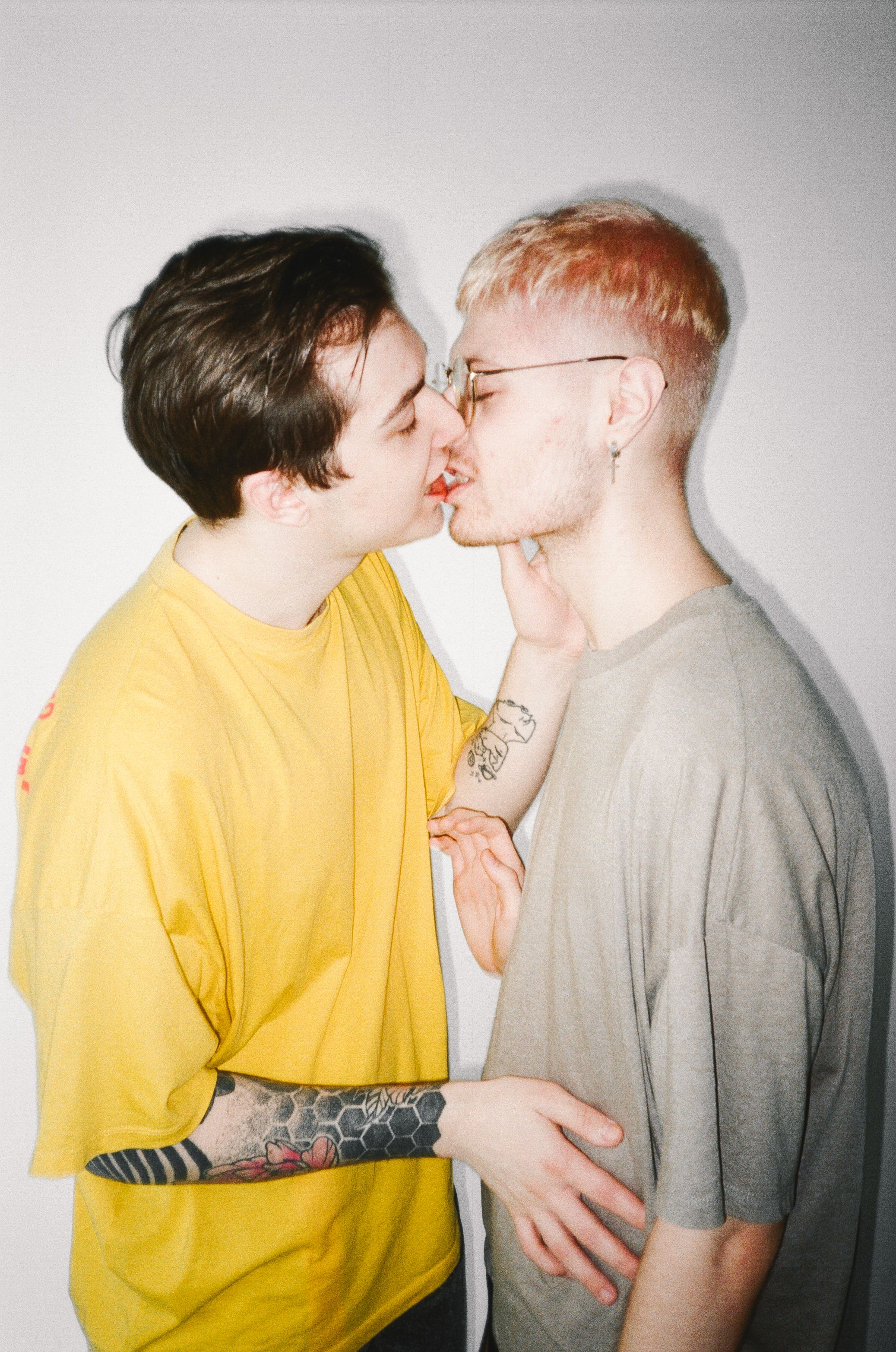 Young LGBT couple sharing a tender kiss indoors, expressing love and pride.