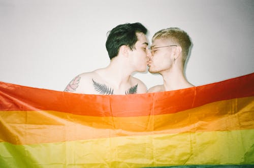 Free Men Behind a Gay Pride Flag Kissing  Stock Photo