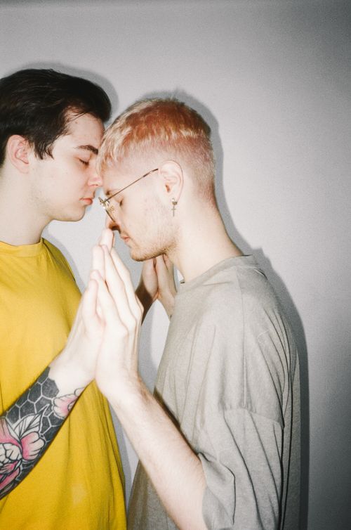 Free Side view of two young men gently touching hands in an intimate, loving moment. Stock Photo