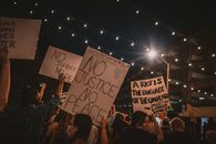 Back view crowd of unrecognizable people holding handmade banners in hands during protest on street at night