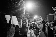 Back view of black and white crowd of unrecognizable protesting people walking on street with banners during anti racism demonstration