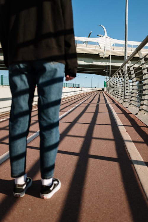 Person in Blue Denim Jeans Standing on Brown Wooden Floor