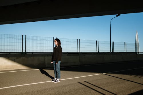 Free Man in Black Jacket and Black Pants Standing on Gray Concrete Road Stock Photo