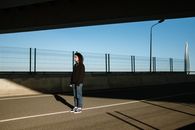 一个孤独的人站在高速公路立交桥下，突显了城市环境中的隔离感
