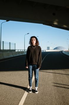一个年轻人站在空荡荡的城市街道的桥下，突显了孤独与城市生活