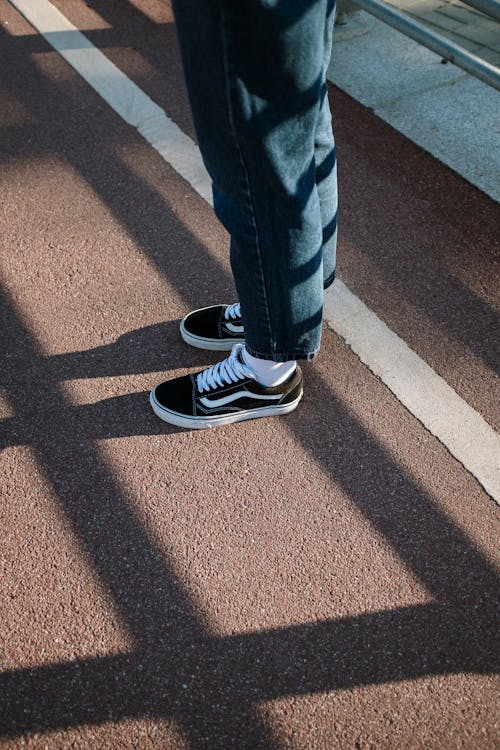 Person in Blue Denim Jeans and Black and White Adidas Sneakers