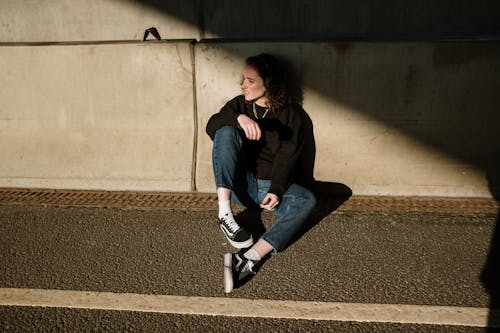 Free Woman in Black Jacket and Blue Denim Jeans Sitting on Concrete Stairs Stock Photo