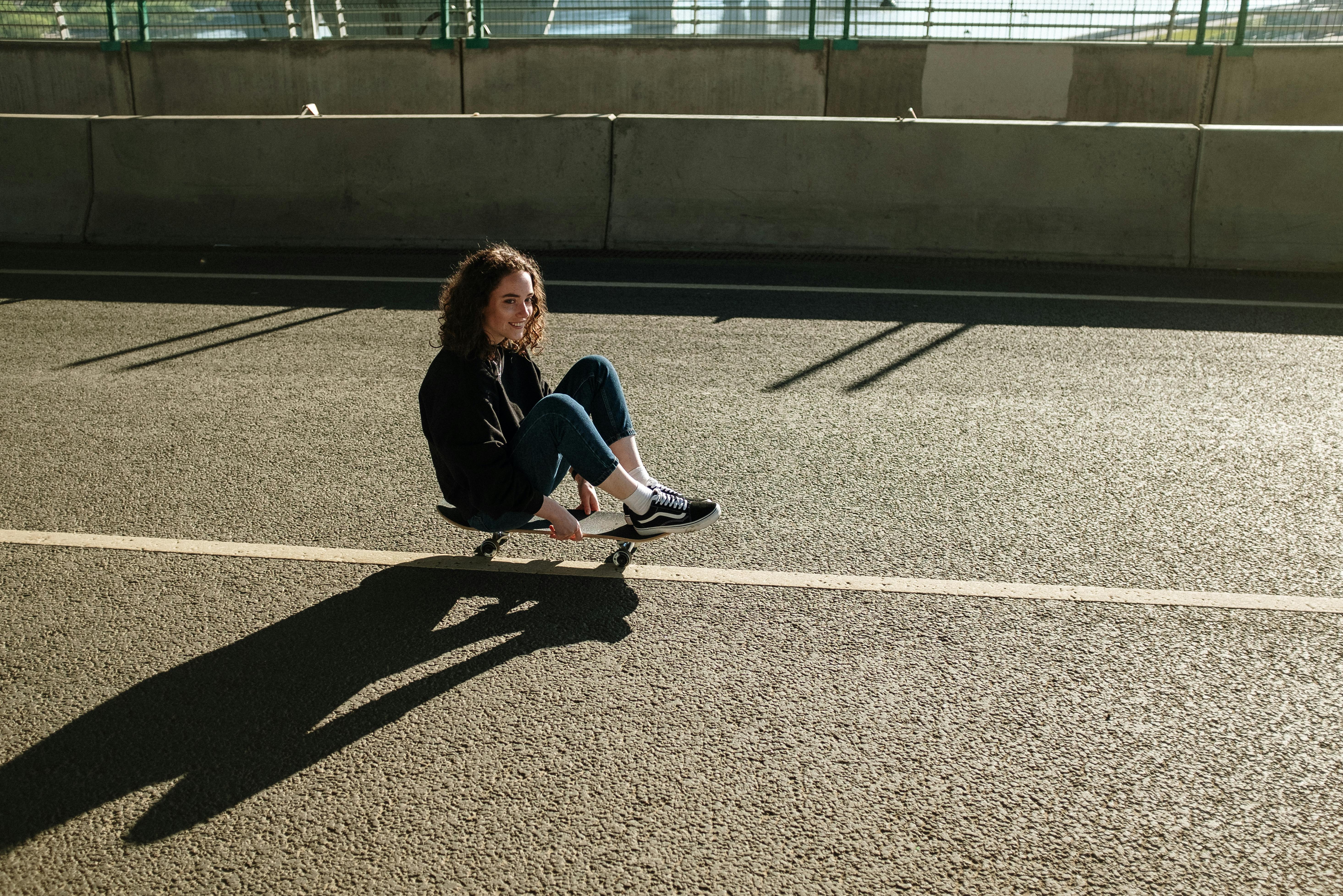 Woman in Black Jacket Sitting on Gray Concrete Floor · Free Stock Photo