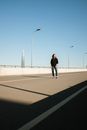 一个女人独自走在空旷的城市公路上，湛蓝的天空下