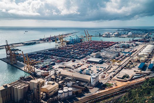 An elevated view of Barcelona's bustling port with cranes and shipping containers.