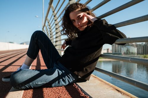 Free A stylish young woman poses on an urban boardwalk, casting intriguing shadows. Stock Photo