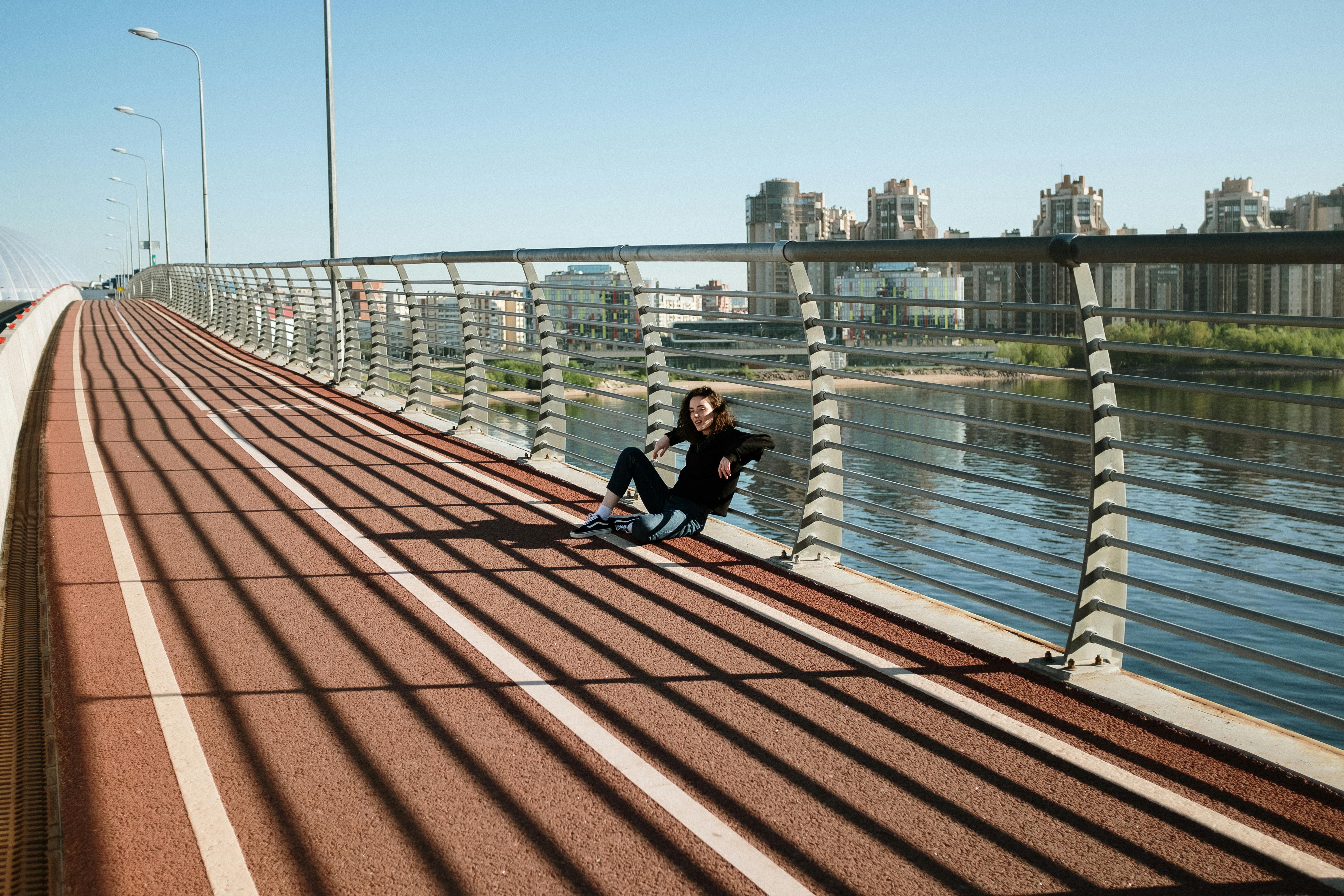 在现代城市桥梁上，一个女人正放松身心，周围是城市景观和长长的阴影