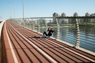 在现代城市桥梁上，一个女人正放松身心，周围是城市景观和长长的阴影