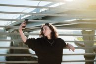 一名年轻女子在阳光下的现代城市桥梁上自拍