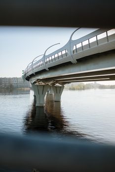 现代桥梁在平静的河流上拱起的动态视图，展现了城市建筑的特色