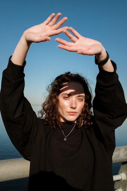 Portrait of a woman with curly hair posing outdoors, showcasing style and expression.
