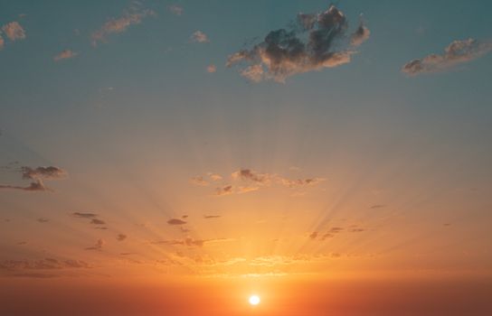 Breathtaking sunset with golden sunbeams and scattered clouds creating a dramatic sky.