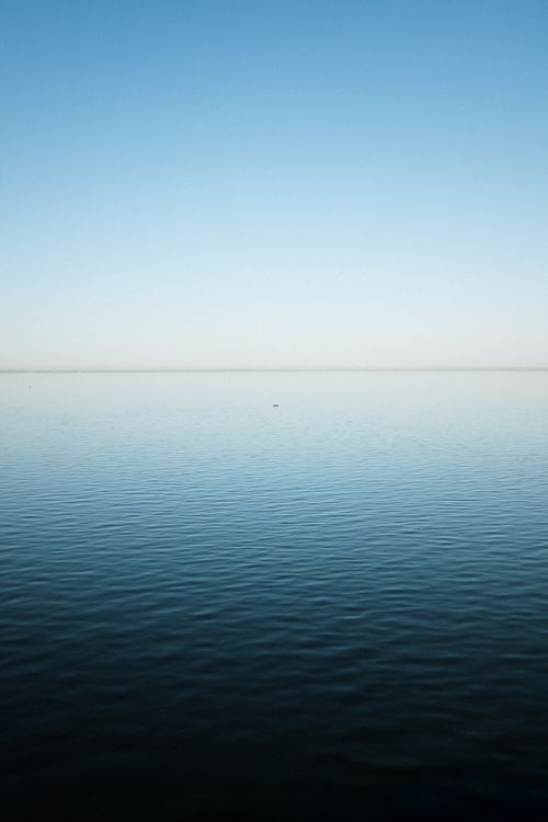 Free A serene view of a calm blue ocean under a clear sky, perfect for relaxation. Stock Photo
