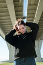 阳光灿烂的日子里，一位年轻女子若有所思地站在一座现代桥下