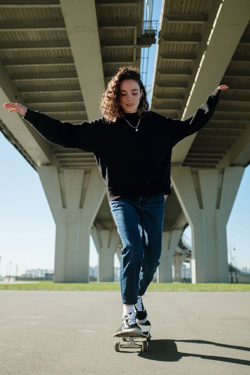 Woman in Black Long Sleeve Shirt and Blue Denim Jeans Standing on Green Grass Field during