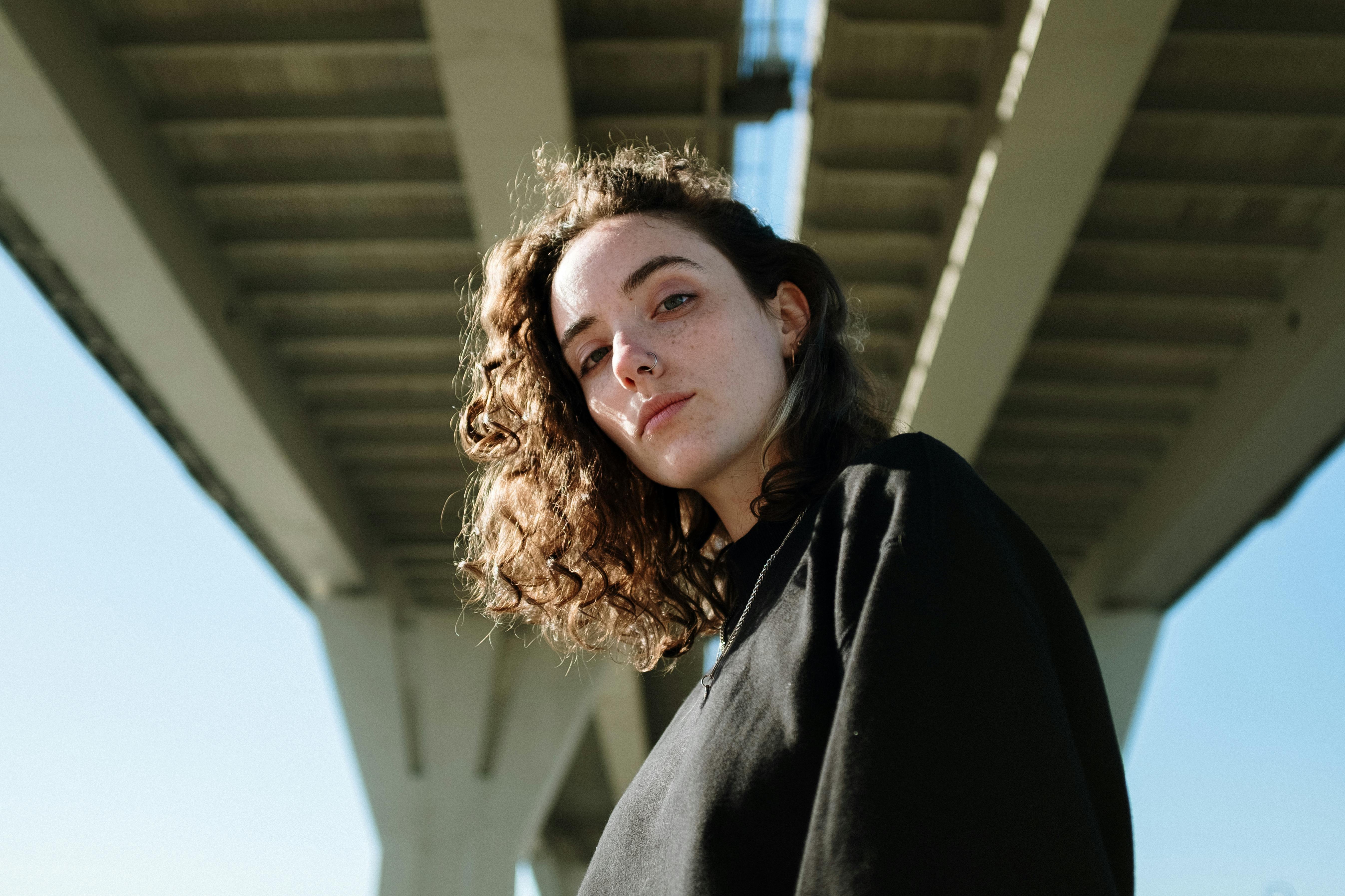 一位卷发女子自信地站在当代桥下