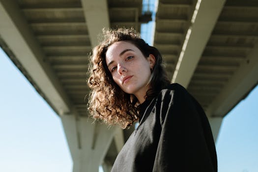 一位卷发女子自信地站在当代桥下