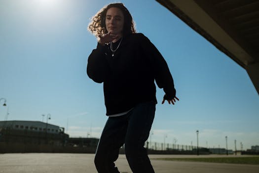 Young woman dancing energetically beneath a modern city bridge in daylight.