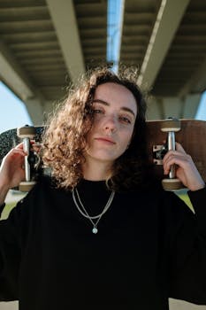 阳光明媚的日子里，一位自信的年轻女子拿着滑板，站在城市桥下