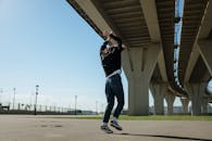 阳光明媚的日子里，一个人在大型城市桥下精力充沛地跳舞