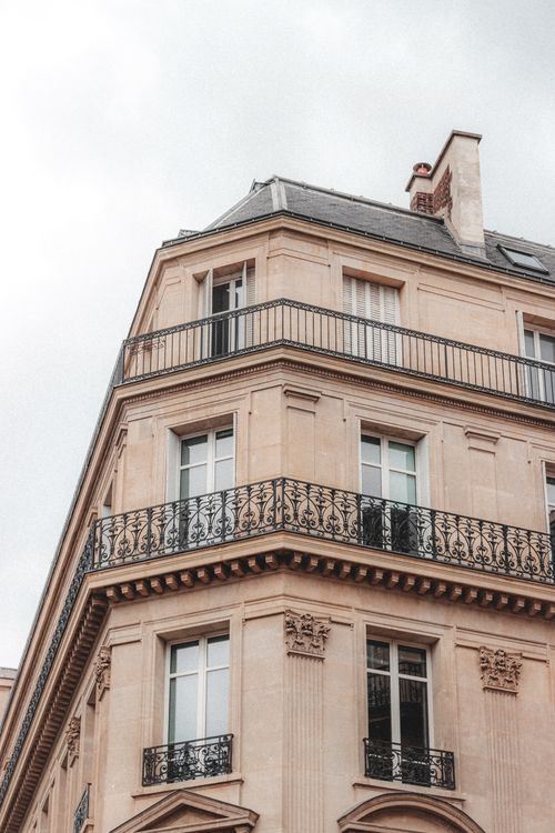Free Exterior of tall beige old historical construction with simple open balconies under grey sky covered with clouds Stock Photo