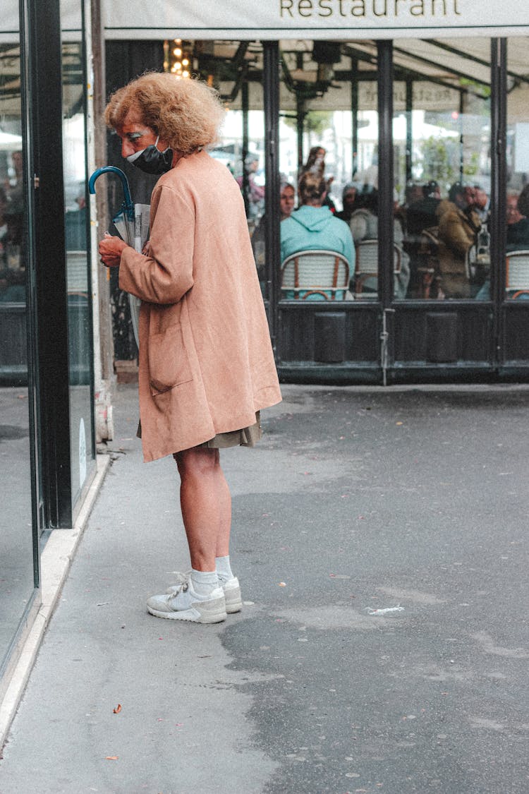 Aged Woman Entering Restaurant On Busy Street