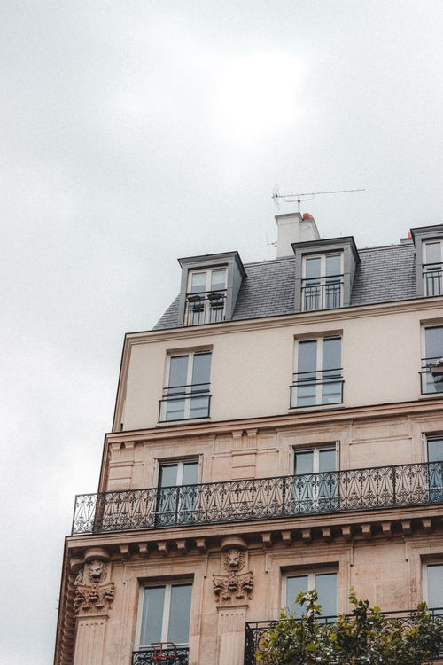 Free Low angle of aged building with ornamental columns and balconies located in residential area under cloudy sky Stock Photo