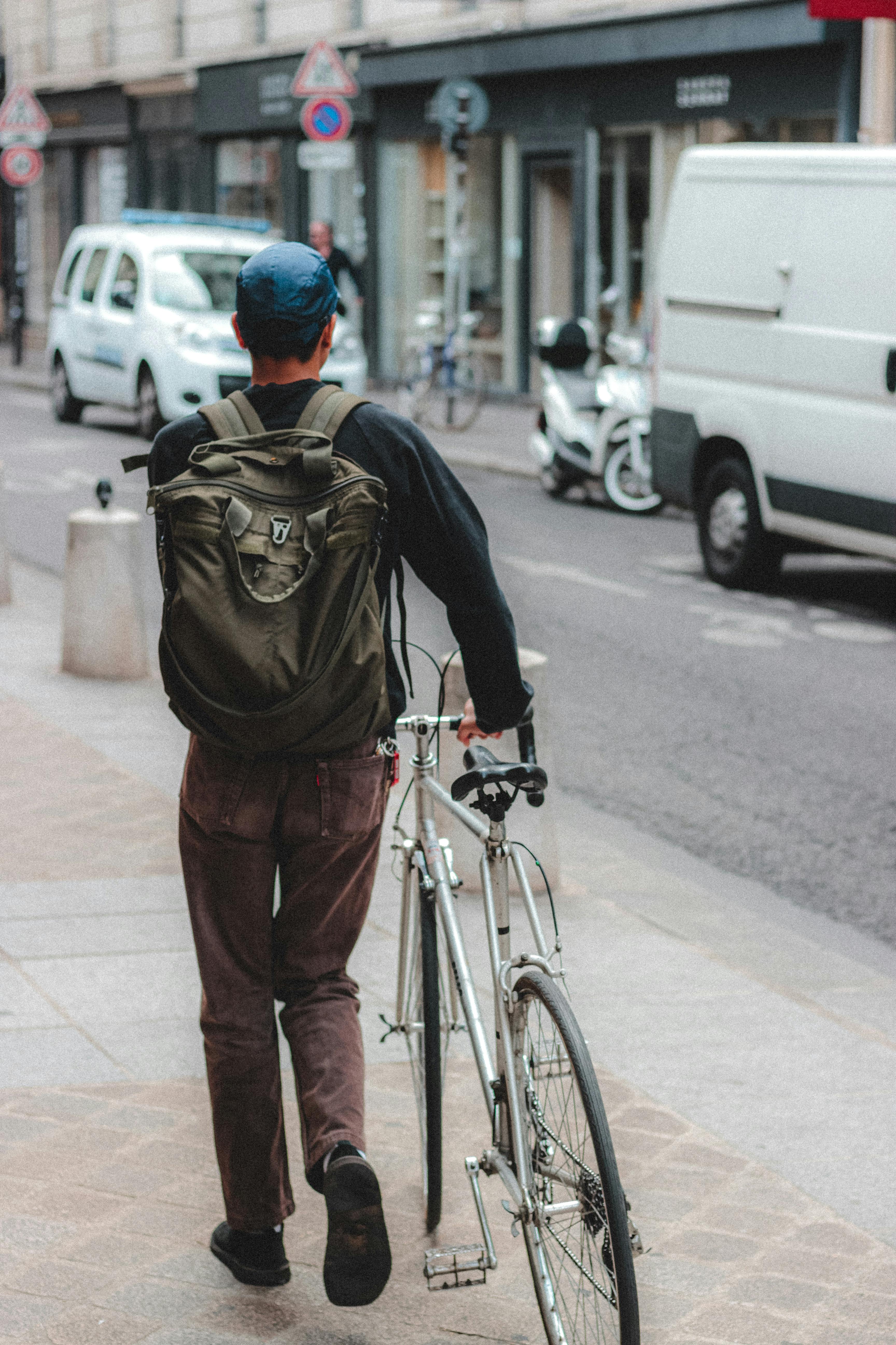 man with bicycle on sidewalk of street