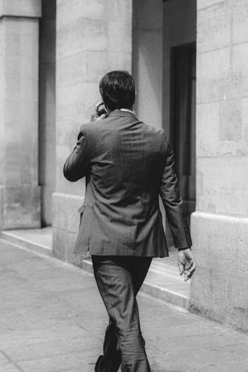 Elegant businessman in suit walking along concrete building