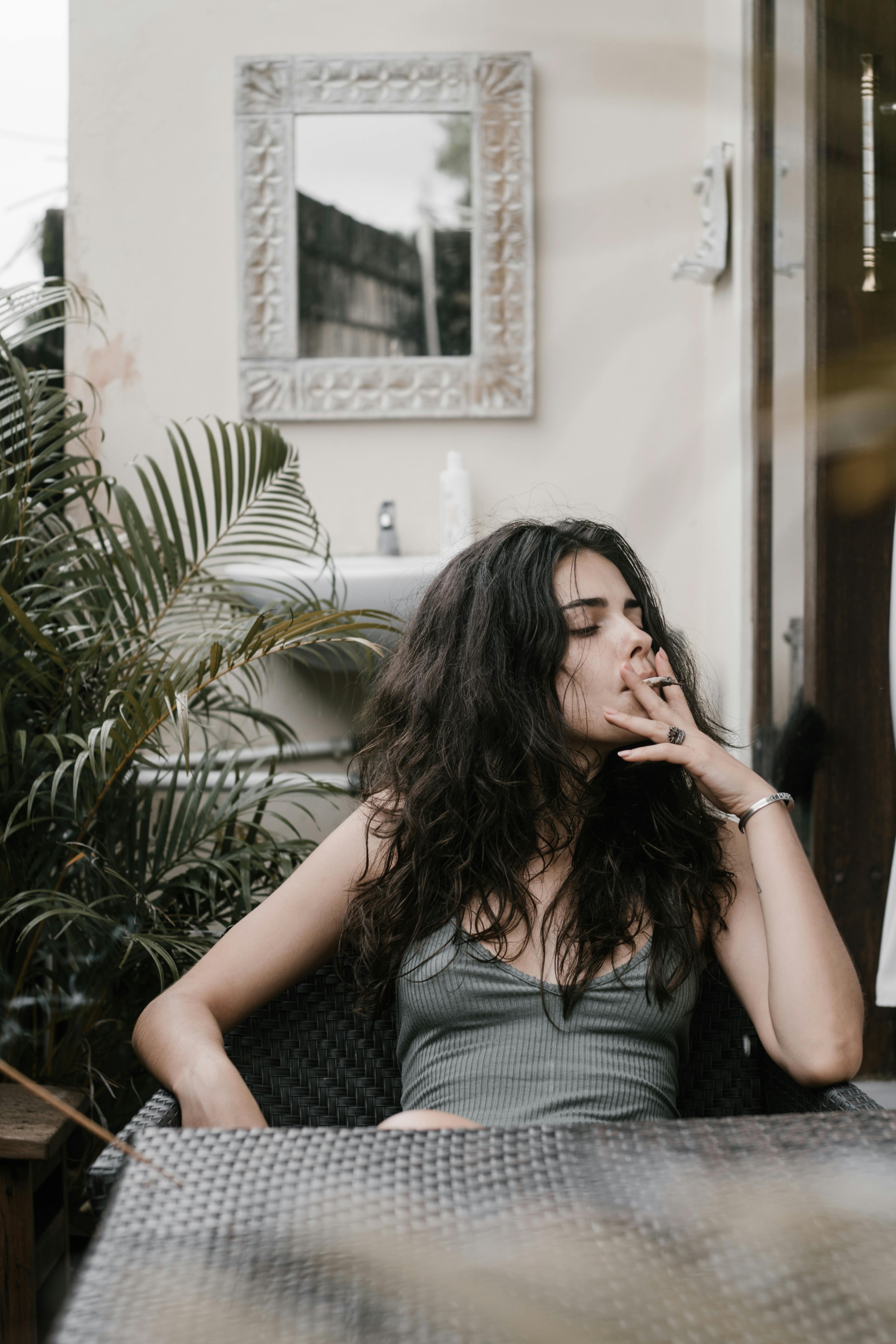 young melancholic woman smoking cannabis joint alone on terrace